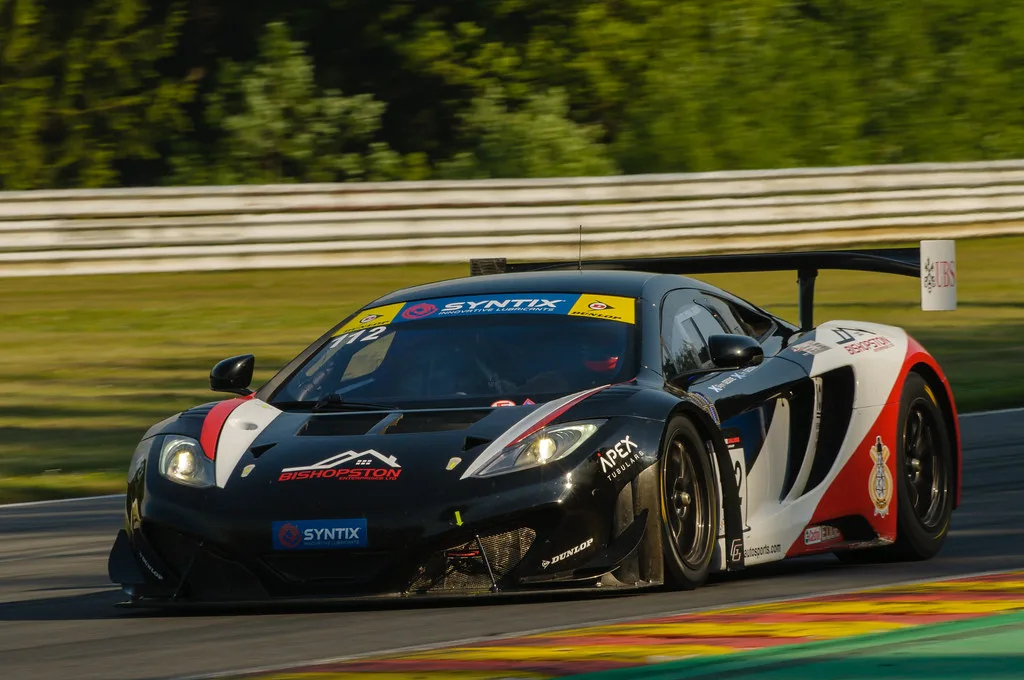 GT-raceauto door een bocht op Circuit de Spa-Francorchamps met het groene Ardense bos op de achtergrond